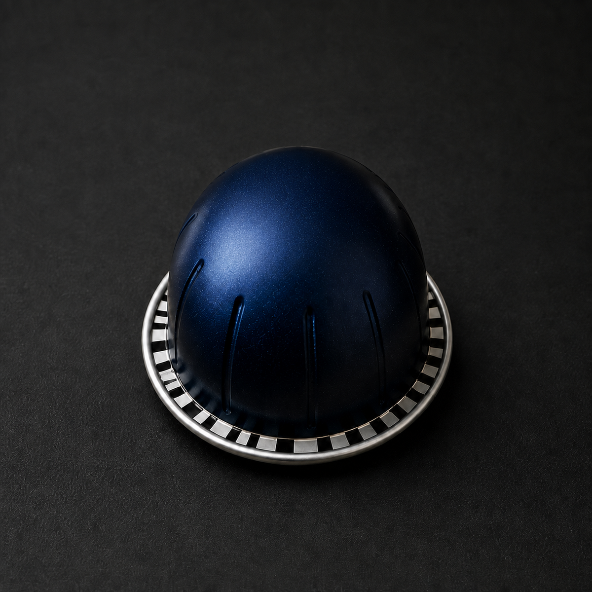 Close-up of an unbranded navy Vertuo-compatible coffee capsule with domed shape and fluted sides